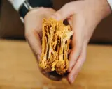 Manos sostienen un trozo de hojaldre casero, mostrando sus finas y crujientes capas doradas.