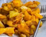 Patatas fritas al horno doradas y crujientes, sazonadas con especias, listas para disfrutar con un tenedor.