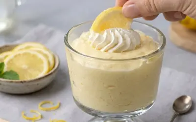 Delicioso mousse de limón receta original, decorado con crema batida y una rodaja de limón.