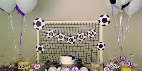 Mesa de chuches del Real Madrid: balones de fútbol, globos, tarta y dulces para una fiesta temática.