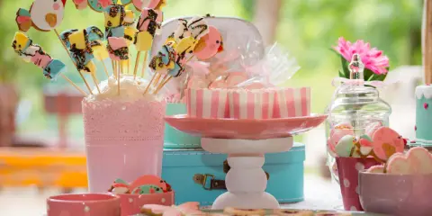 Una encantadora mesa de chuches casera con galletas de pájaros, malvaviscos y dulces en tonos pastel.