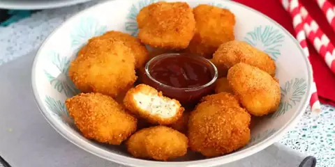 Un plato lleno de crujientes nuggets caseros, listos para mojar en salsa barbacoa.