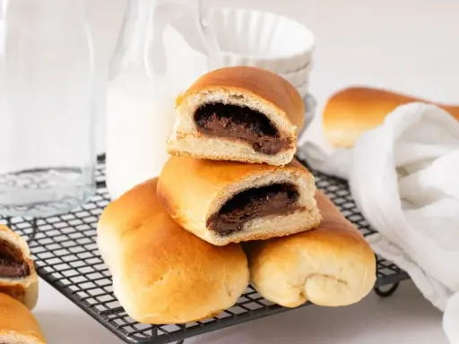 Bollo de chocolate recién horneado, con relleno cremoso, apilado sobre una rejilla.