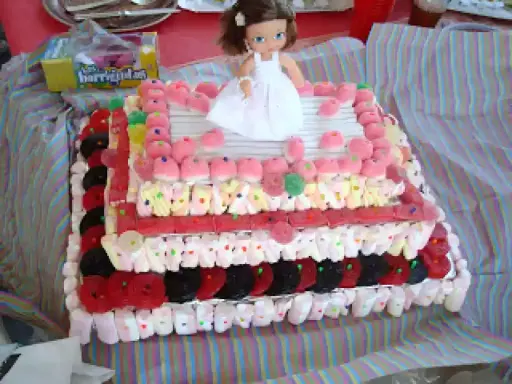 Un pastel de xuxes con una muñeca en la cima, decorado con malvaviscos, gominolas y caramelos.
