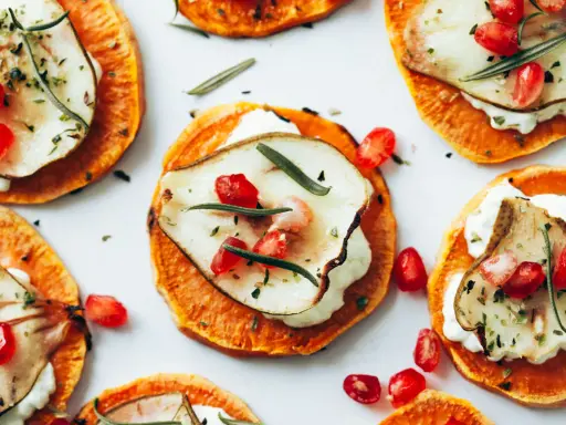 Deliciosas rodajas de boniato asado con queso cremoso, pera, granada y romero. Ideales para recetas con boniato.