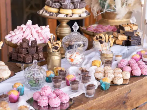 Una mesa dulce boda original con donuts, brownies, malvaviscos rosas y bolitas de colores.