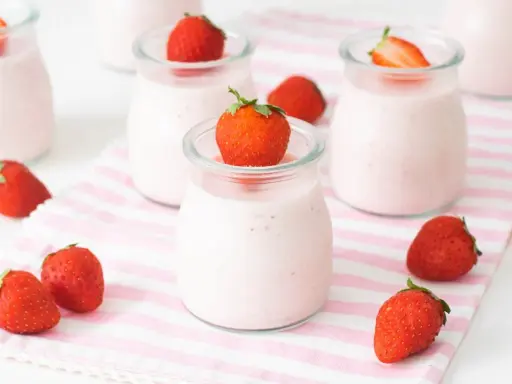 Deliciosos petit yogures de fresa en vasitos de cristal, decorados con fresas frescas.