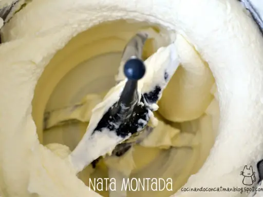Batidora con pala mezclando nata montada, creando una textura esponjosa y cremosa, lista para postres.