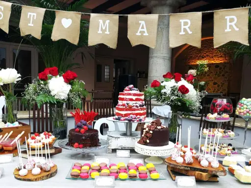 Una mesa de dulces sencillas para una celebración, con pasteles, macarons y cake pops.