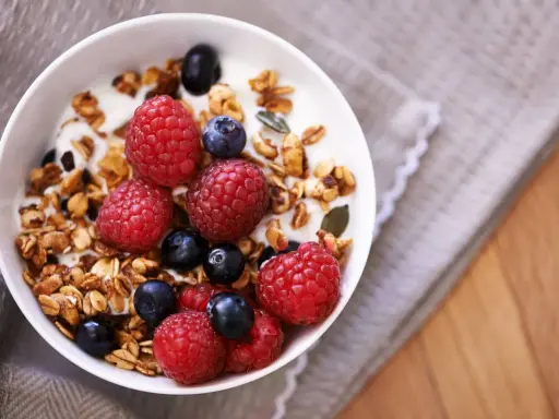 Un tazón de yogur con granola casera, frambuesas y arándanos. Un desayuno saludable y delicioso.