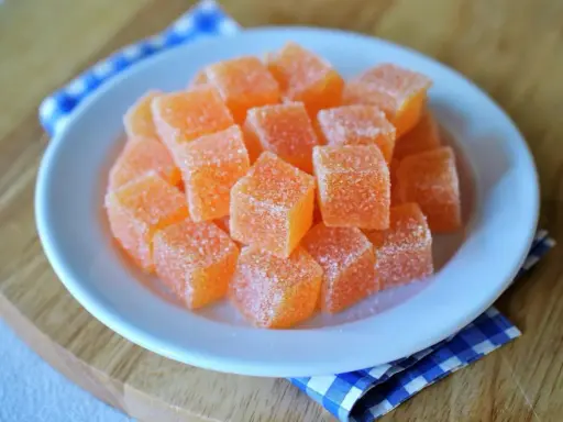 Dulces cubos de naranja cubiertos de azúcar, perfectos para aprender como hacer chuches caseras.