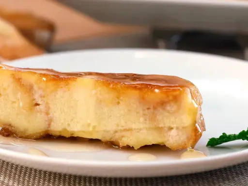Un trozo de pan de calatrava bañado en caramelo, con una hoja de menta al lado.