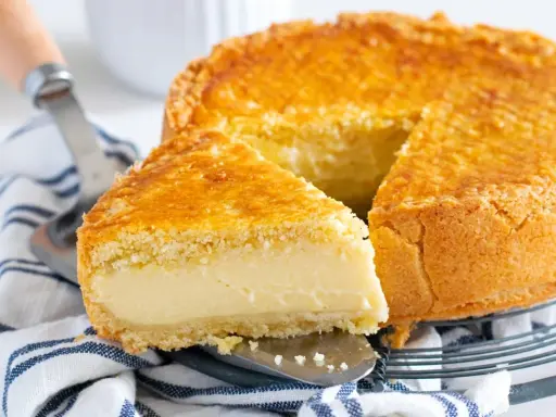 Un delicioso pastel vasco con una porción cortada, mostrando su relleno cremoso y su dorada corteza.