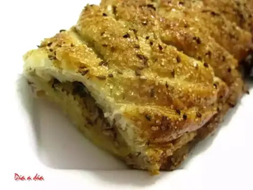 Deliciosa trenza de hojaldre dorada, espolvoreada con azúcar y semillas, lista para disfrutar.