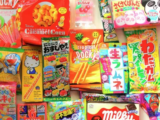 Un surtido vibrante de chuches famosas japonesas, incluyendo Pocky, Caramel Corn y dulces de Hello Kitty y Doraemon.