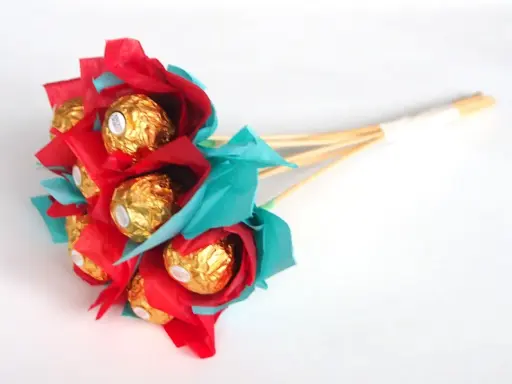 Un ramo de bombones dorados envueltos en papel rojo y turquesa, ideal para un regalo dulce y original.
