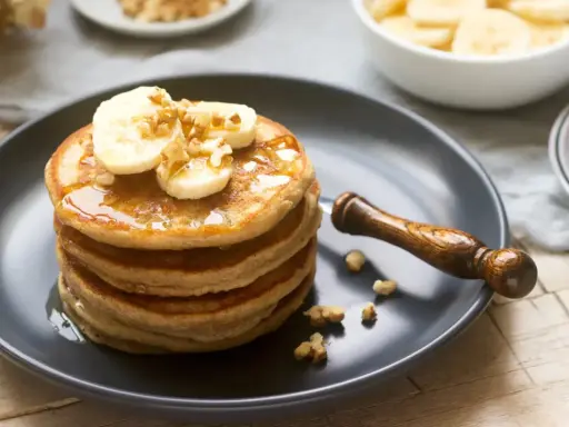 Pila de tortitas americanas con plátano y nueces, bañadas en sirope. Un desayuno perfecto.