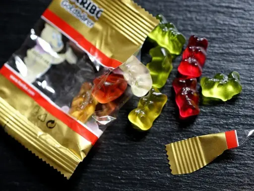 Osos de goma Haribo de colores esparcidos sobre una superficie oscura. ¡Cuidado, las chuches caducan!