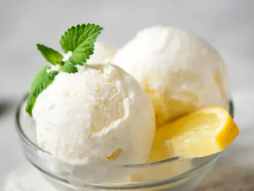 Delicioso helado de limón casero en copa de cristal, adornado con menta fresca y rodajas de limón.