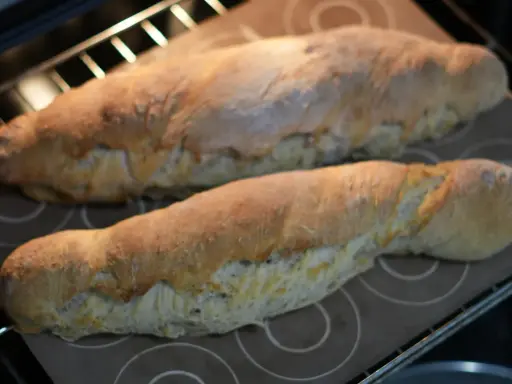 Dos panes dorados recién horneados, hechos con la ayuda de la Thermomix, reposan sobre una bandeja en el horno.