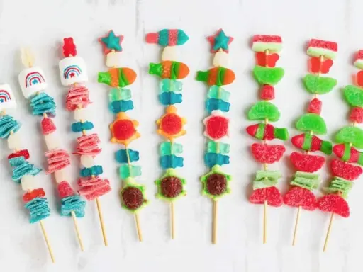 Brochetas de chuches con formas de animales y arcoíris, listas para envolver y disfrutar.