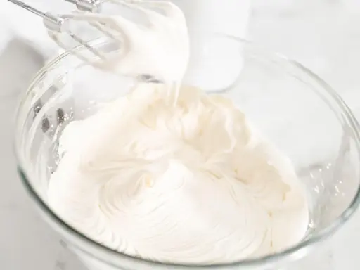 Batidora eléctrica batiendo para crear una deliciosa nata montada en un bol de cristal.