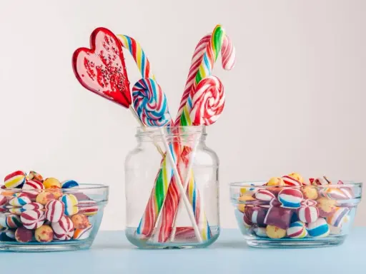Dulces coloridos y piruletas en forma de corazón y espiral, perfectos para manualidades como regalar chuches.