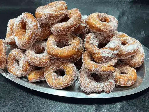 Montón de buñuelos de cuaresma espolvoreados con azúcar, listos para disfrutar.
