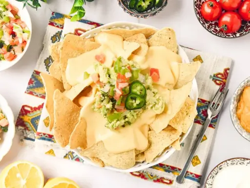 Nachos con queso cubiertos de guacamole y pico de gallo, listos para disfrutar.