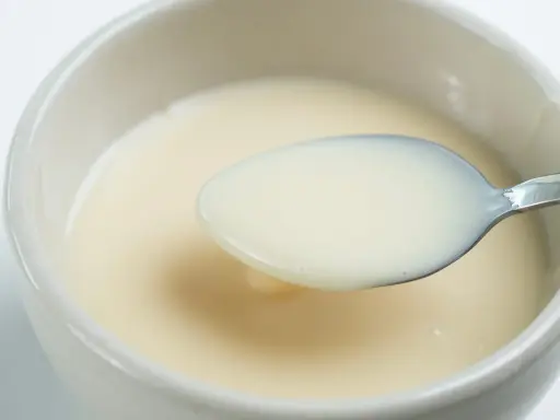 Cuchara con leche evaporada, un ingrediente cremoso y versátil.