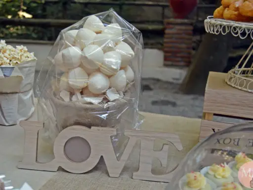 Mesa dulce con palomitas, merengues, cupcakes y letras de madera "LOVE".