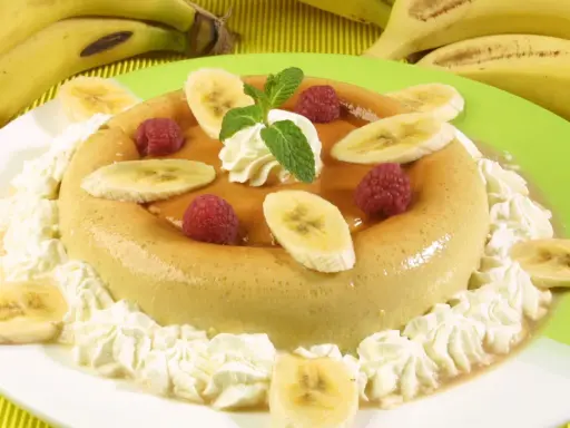Delicioso flan de plátano adornado con rodajas de plátano, frambuesas y crema batida. Un postre perfecto para cualquier ocasión.