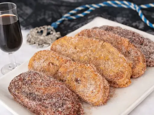 Torrijas cubiertas de azúcar y canela, listas para disfrutar. Un delicioso pan para torrijas, acompañado de una copa de vino dulce.