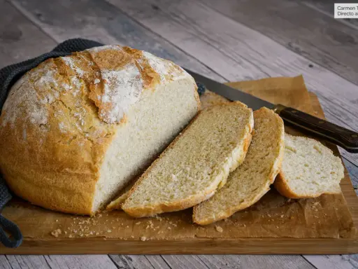 Un delicioso pan casero con levadura fresca, recién horneado y cortado en rebanadas sobre una tabla de madera.