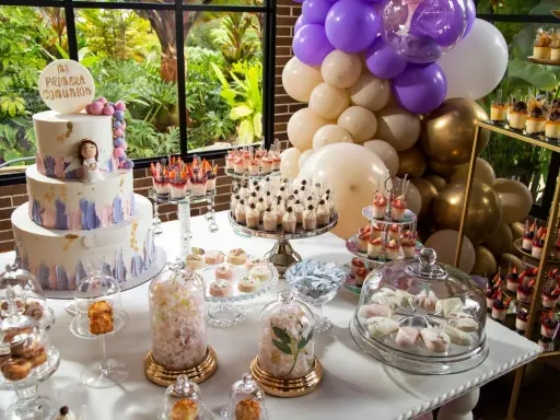 Mesa dulce para comunión con pastel, postres individuales, dulces y globos.