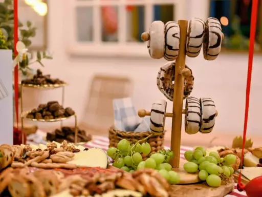Deliciosa merienda de cumpleaños para adultos: donuts, quesos, frutos secos y uvas.