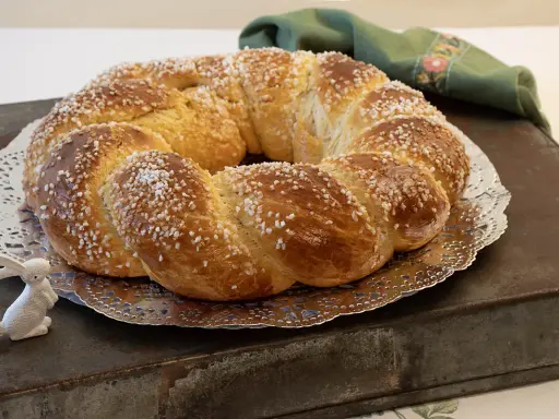 Rosca de Pascua gallega, trenzada y espolvoreada con azúcar, junto a un conejito blanco.