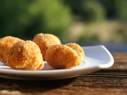Croquetas caseras doradas y crujientes en un plato blanco, listas para disfrutar.