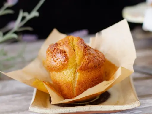 Un muffin dorado, recién horneado, envuelto en papel de horno. Perfecto para acompañar tu proceso de hacer masa madre.