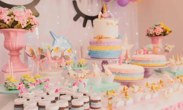 Mesa de dulces temática de unicornios con pasteles, galletas, cupcakes y más postres para una fiesta mágica.