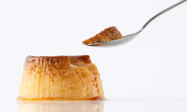 Un trozo de flan casero sin horno en una cuchara, con el resto del postre caramelizado al lado.