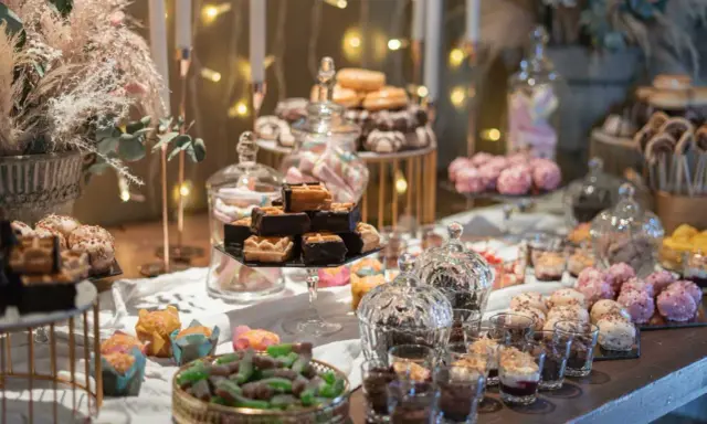 Mesa dulce con variedad de postres, incluyendo un candy bar rústico con chocolates y galletas.