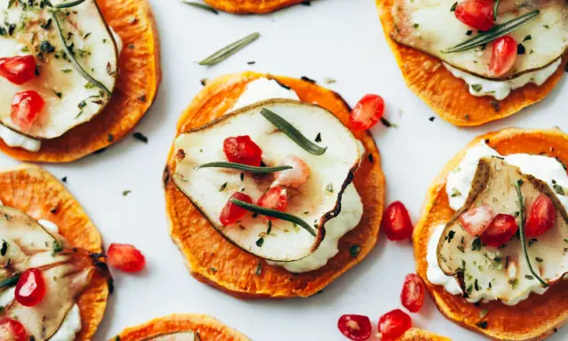 Deliciosas rodajas de boniato asado con queso cremoso, pera, granada y romero. Ideales para recetas con boniato.