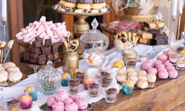 Una mesa dulce boda original con donuts, brownies, malvaviscos rosas y bolitas de colores.