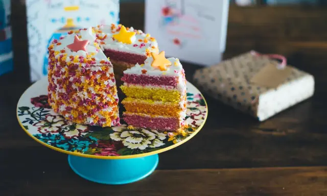 Pastel de capas arcoíris con estrellas de azúcar y chispas. ¡Ideas para decorar tartas que inspiran alegría y color!