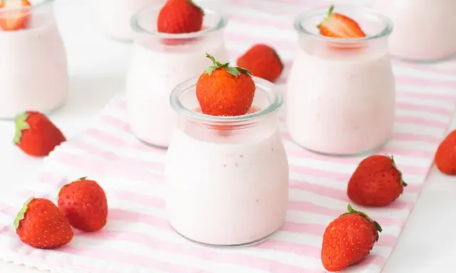 Deliciosos petit yogures de fresa en vasitos de cristal, decorados con fresas frescas.