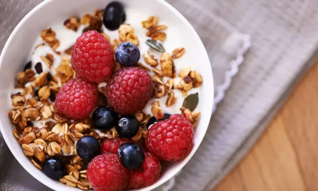 Un tazón de yogur con granola casera, frambuesas y arándanos. Un desayuno saludable y delicioso.