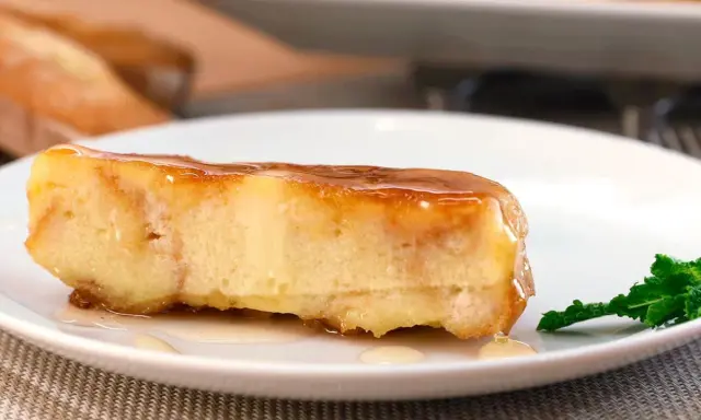 Un trozo de pan de calatrava bañado en caramelo, con una hoja de menta al lado.