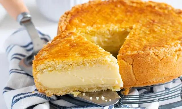Un delicioso pastel vasco con una porción cortada, mostrando su relleno cremoso y su dorada corteza.