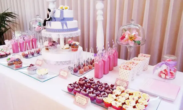 Mesa dulce para 50 cumpleaños con pastel de dos pisos, cupcakes, cake pops, bebidas rosas y palomitas.